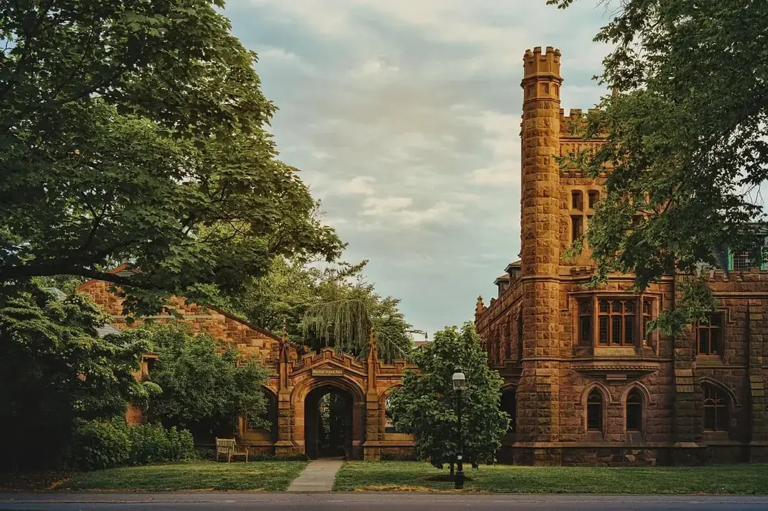 A Gothic stone university building behind a gated archway