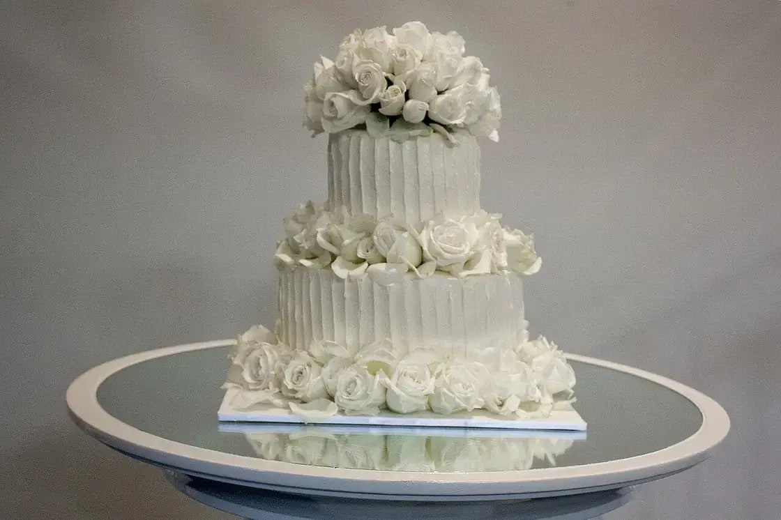 A two-tier buttercream wedding cake decorated with fresh white roses