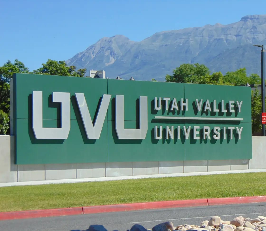 The Utah Valley University monument sign on the main campus in Orem, Utah, with Mount Timpanogos rising behind it