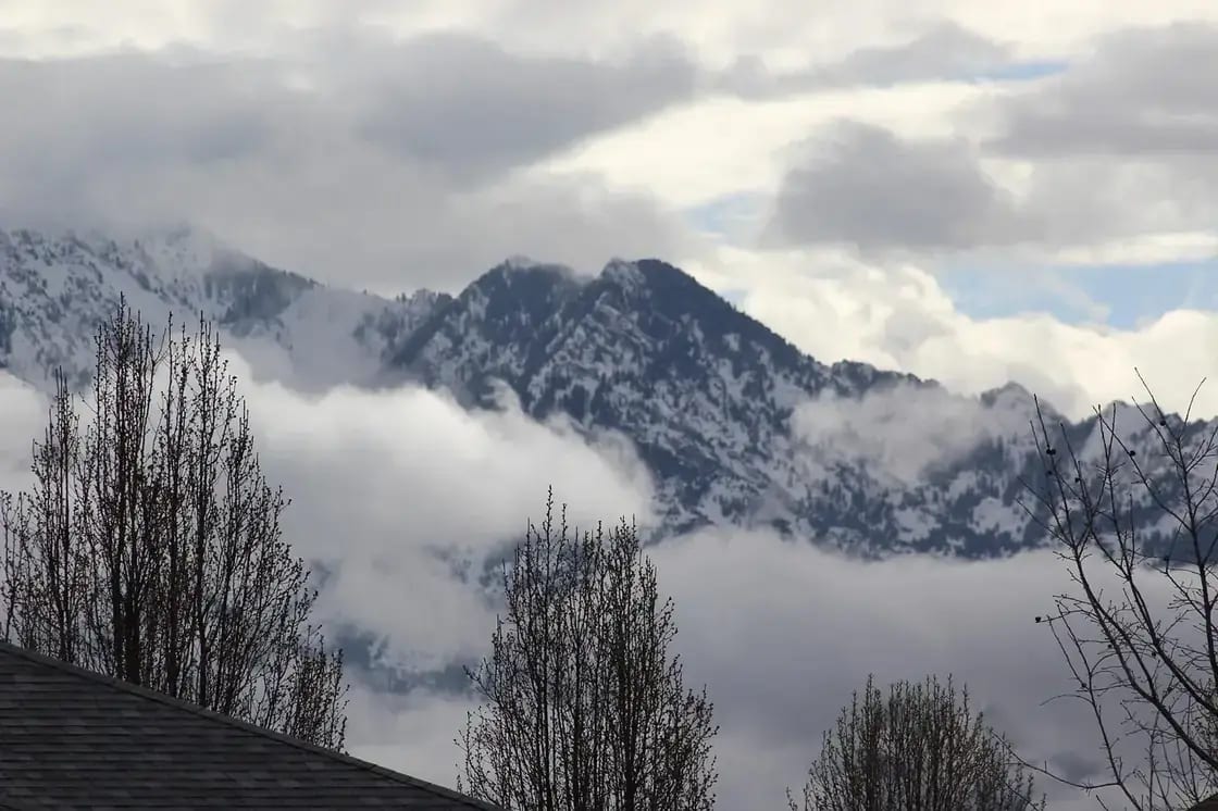 Snow-covered mountain peaks rising above low cloud