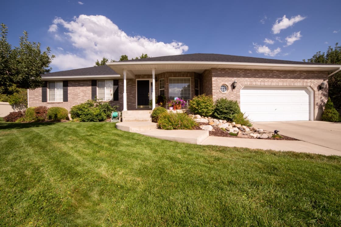 A single-story brick home with a lawn and tidy front landscaping