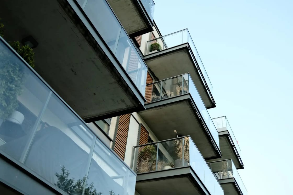 Glass-fronted balconies stacked along the side of a modern apartment building