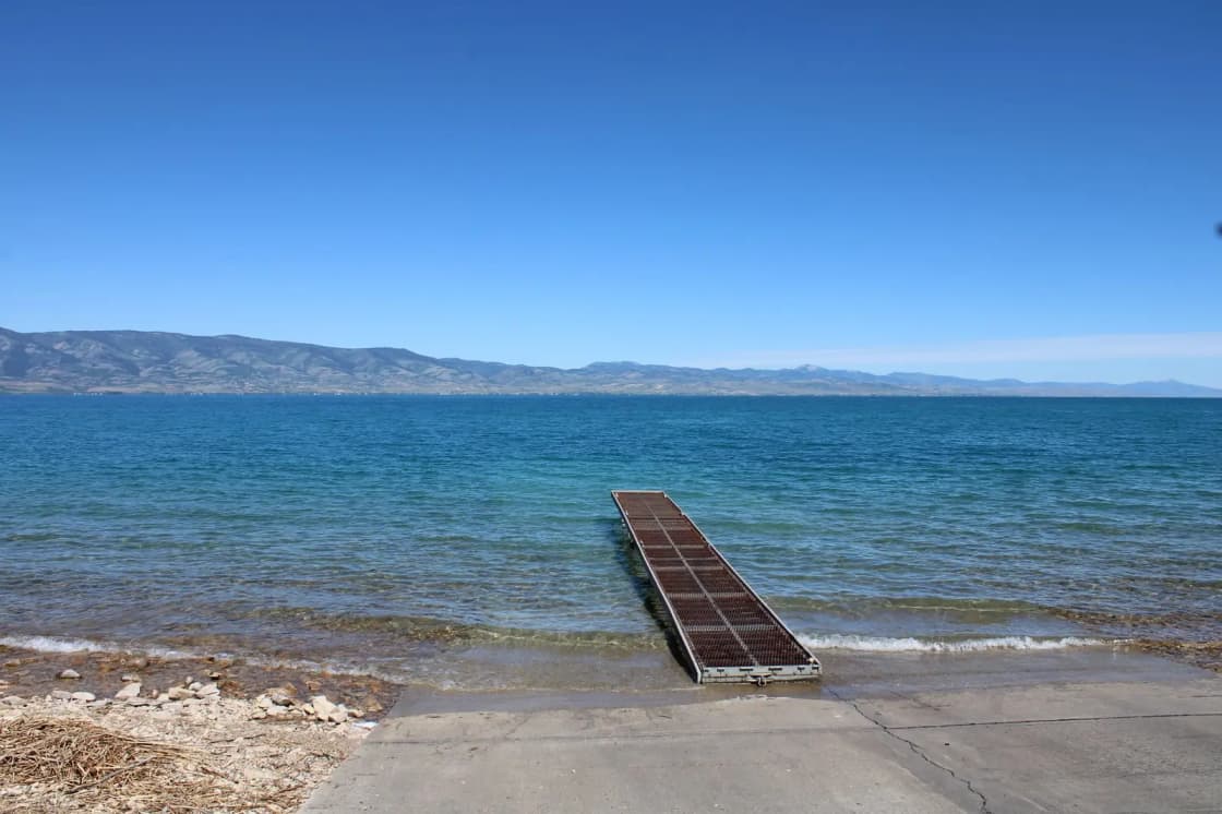 Serene view of a pier going into a clear blue lake with mountain backdrop