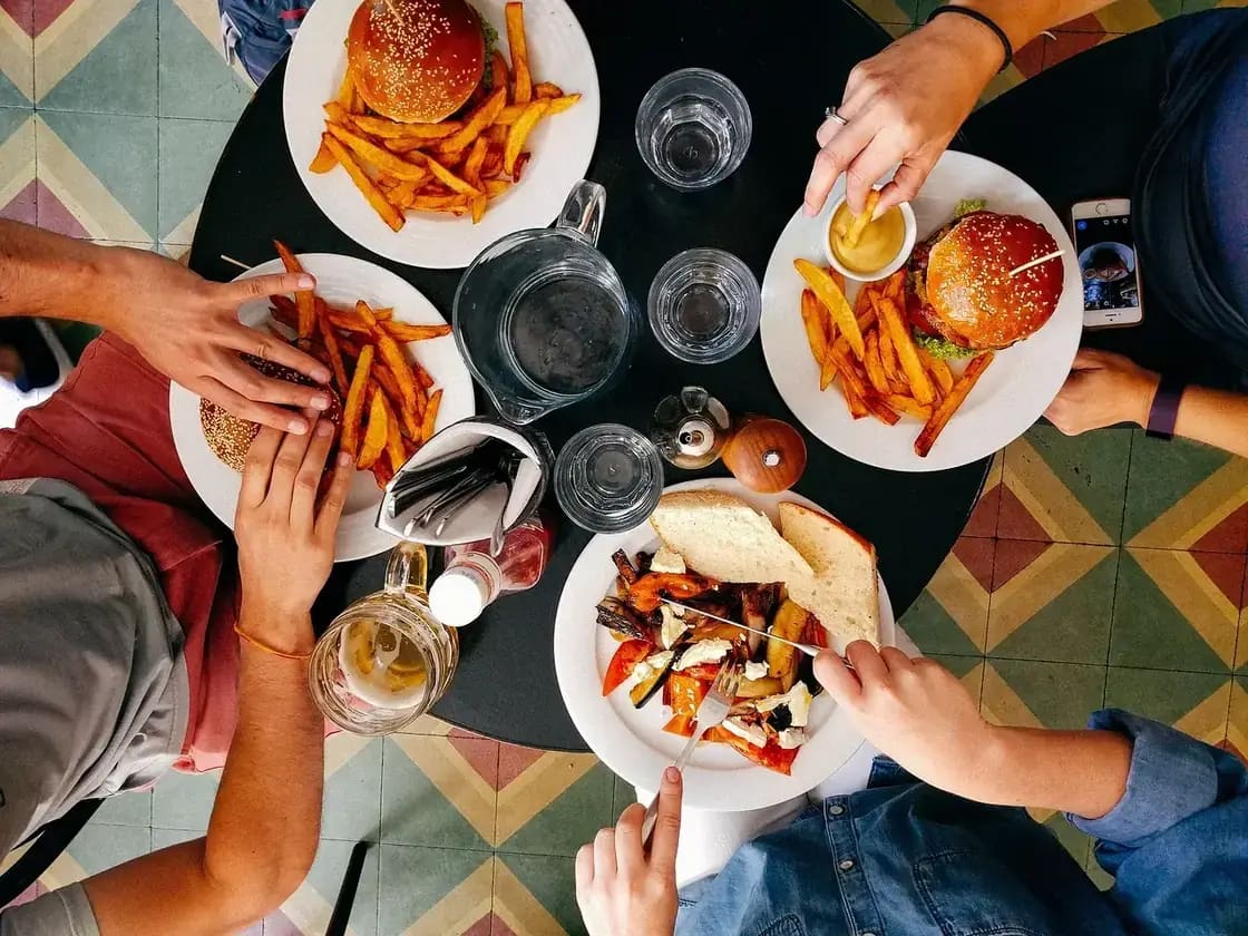 Four people sharing burgers and fries around a restaurant table, seen from above