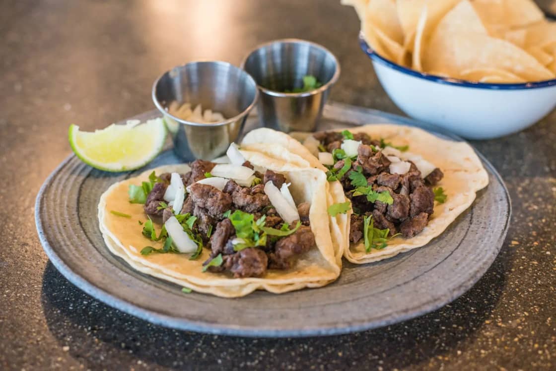 Beef tacos topped with cilantro and lime on a plate