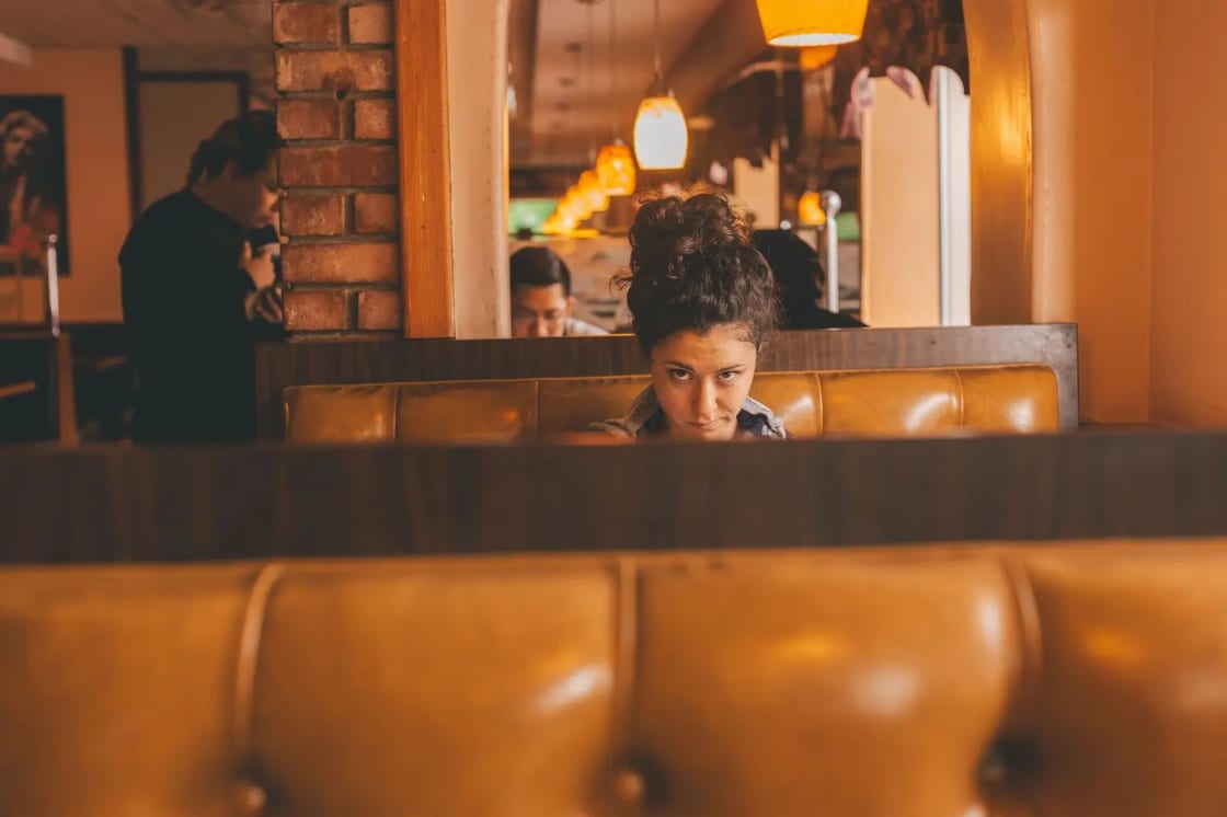 Warm and inviting restaurant interior with a woman seated in a booth