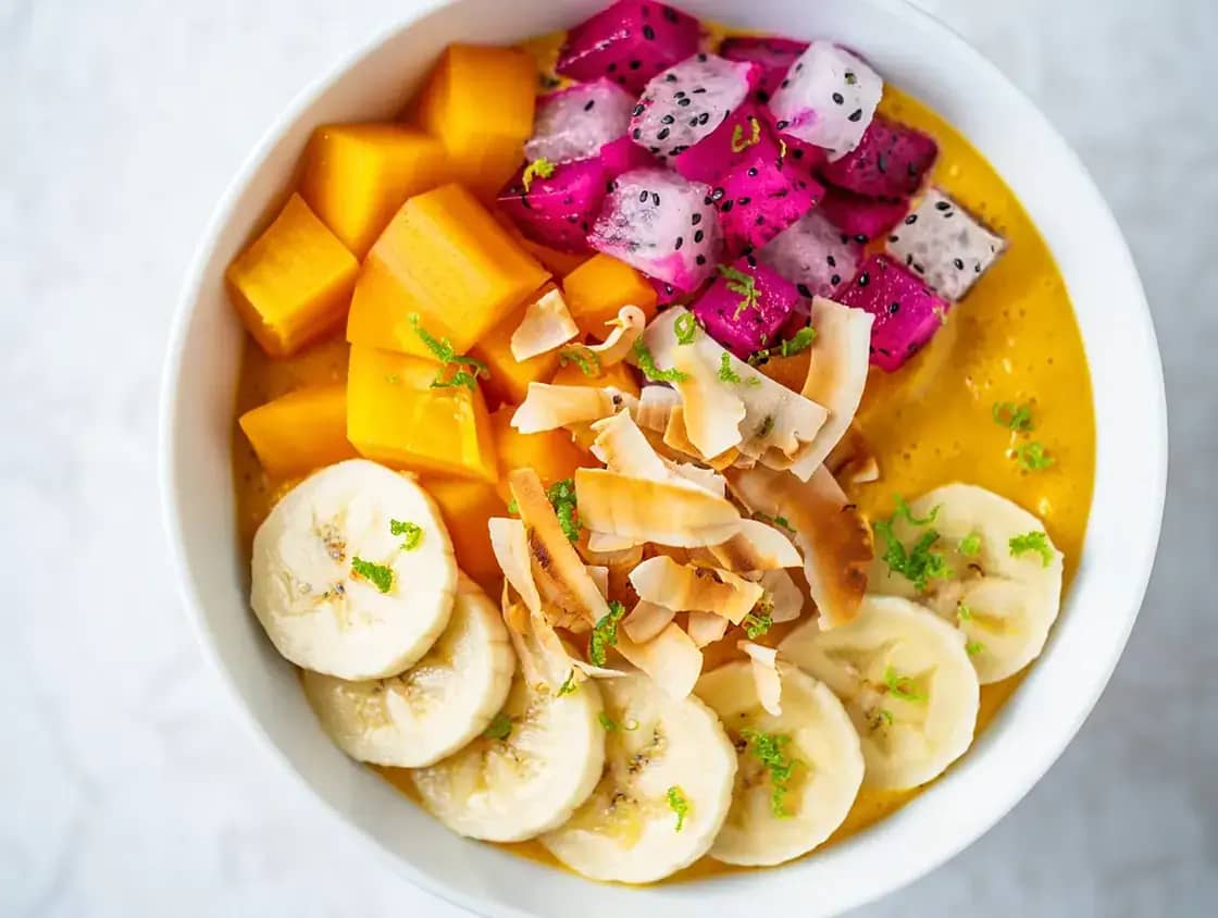 A smoothie bowl topped with mango, dragon fruit, banana and coconut