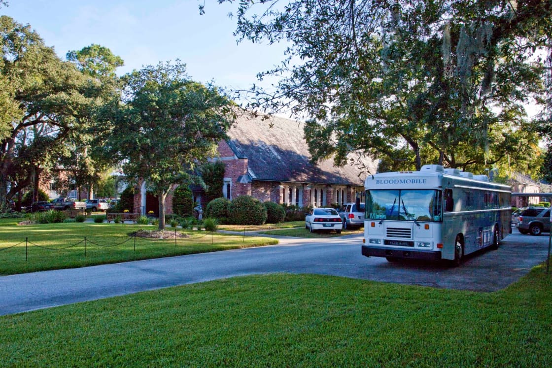 A bloodmobile parked on a church driveway for a community blood drive