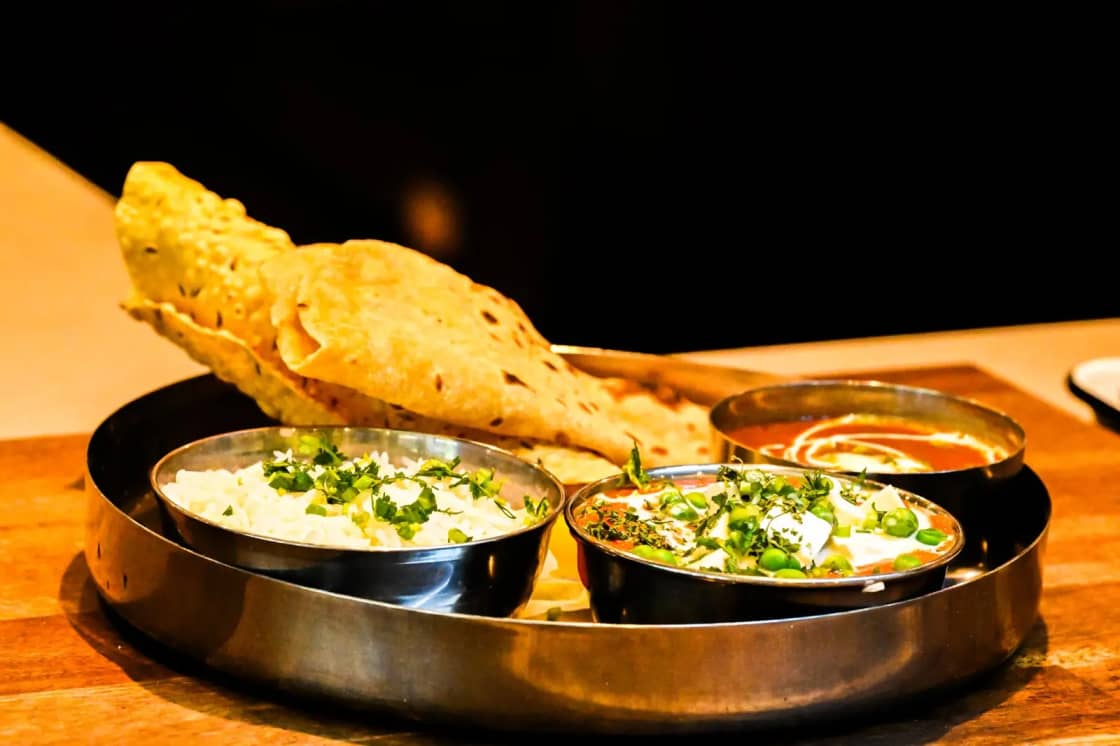 An Indian thali with naan, paneer curry and rice