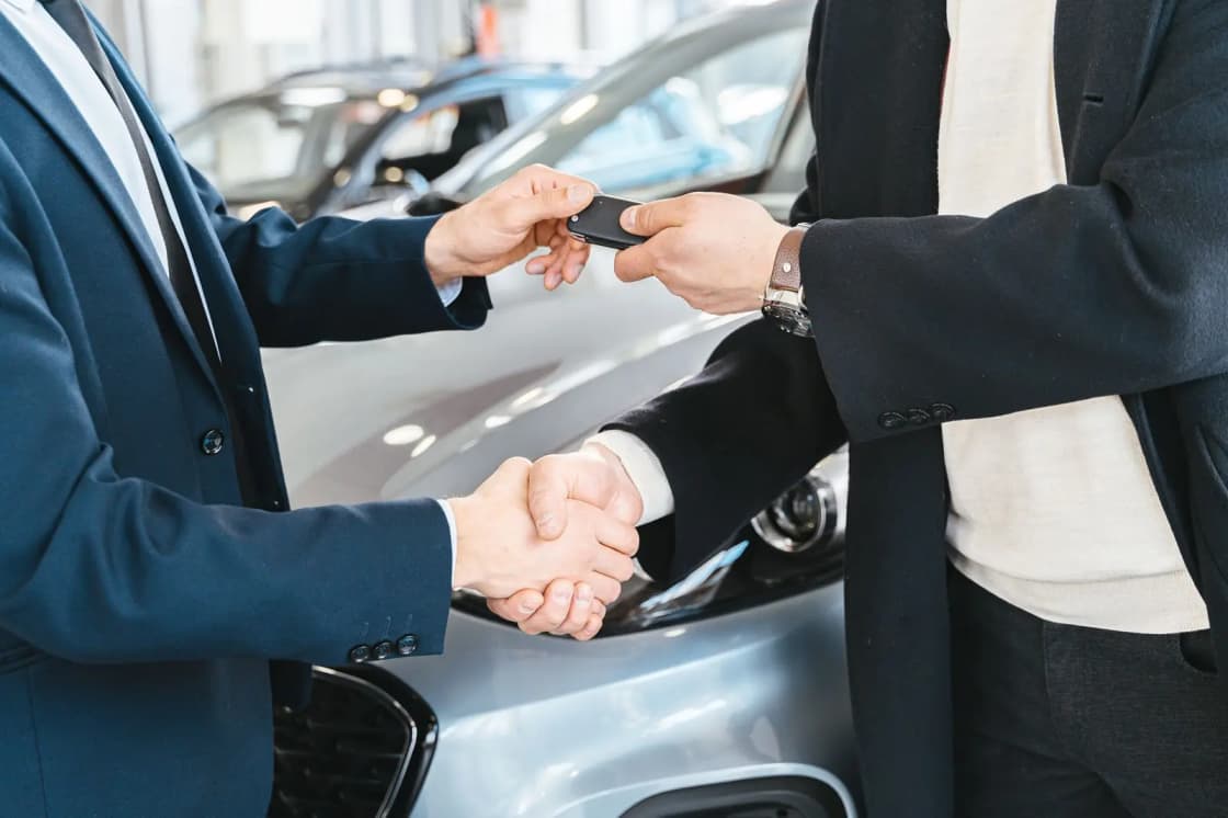 Two people shaking hands as car keys change hands