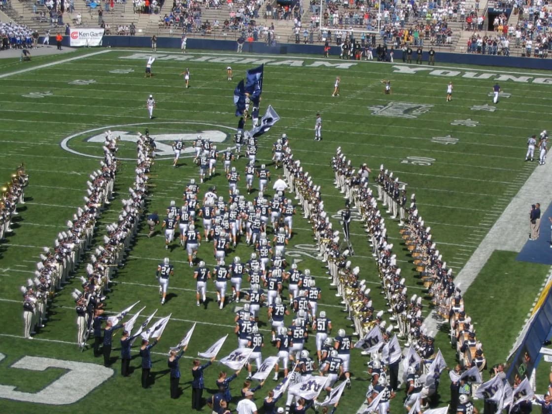 The BYU football team running onto the field at LaVell Edwards Stadium as the band forms up