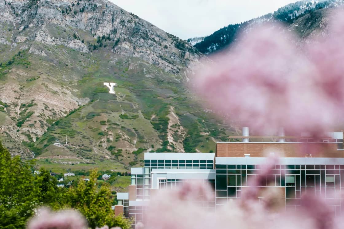 The block Y on Y Mountain above BYU's Life Sciences Building in Provo, seen past blurred pink lilac blossoms in spring.