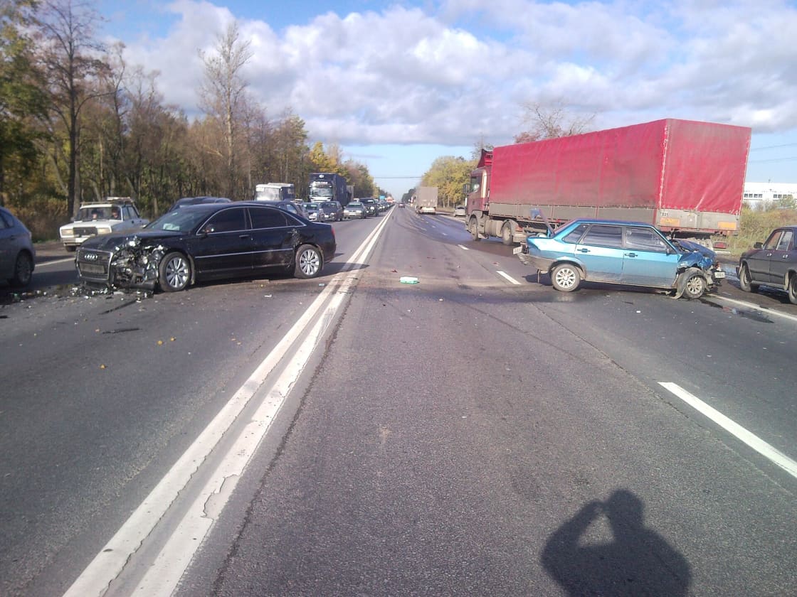 A multi-vehicle collision blocking both lanes of a highway, with a red semi-trailer stopped across the road