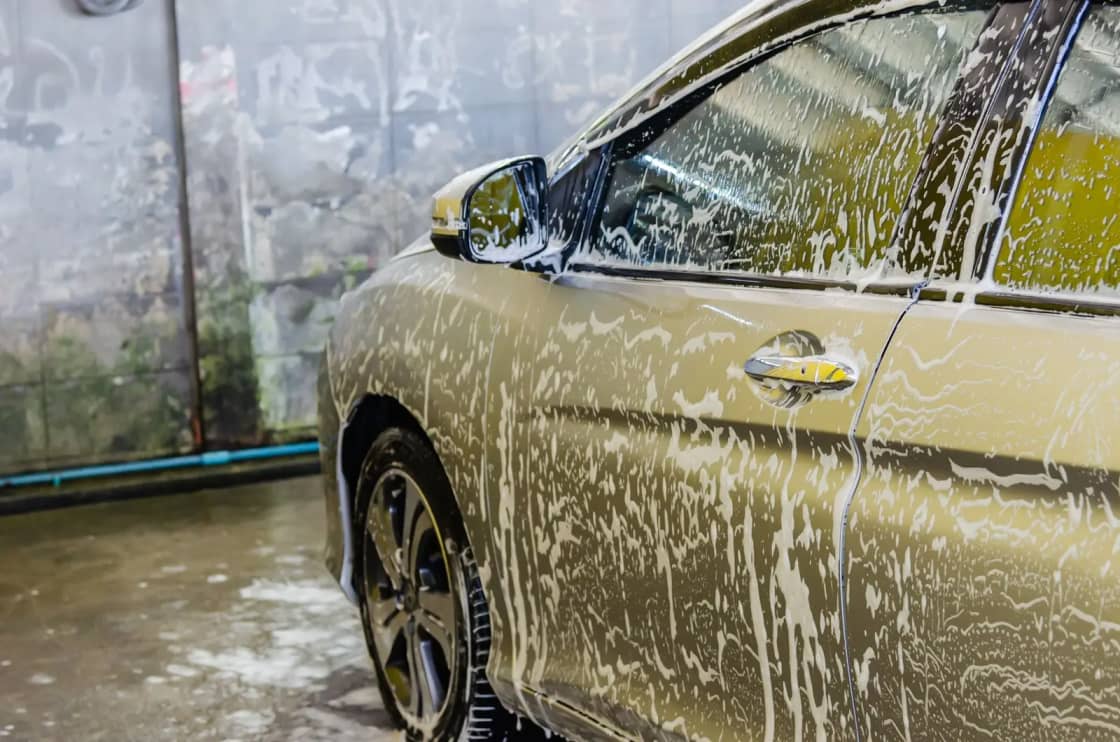 A car being washed with soap at a car wash service, highlighting cleaning and care