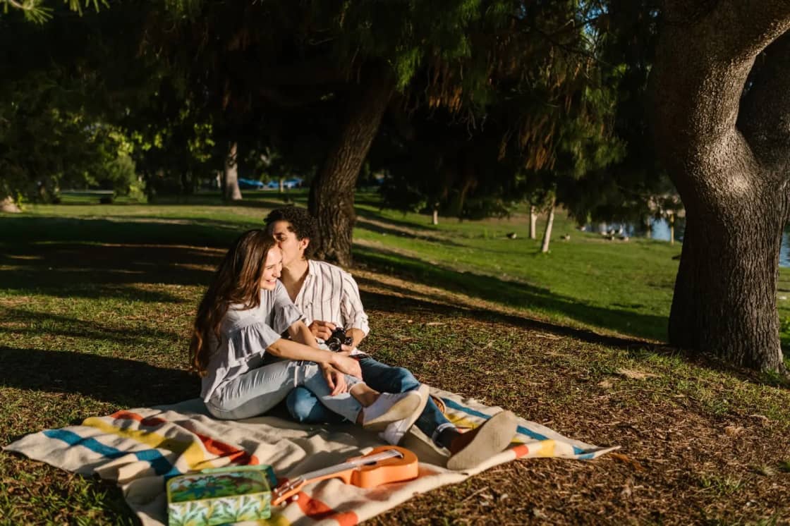Young couple sharing a romantic picnic in a lush green park under the trees