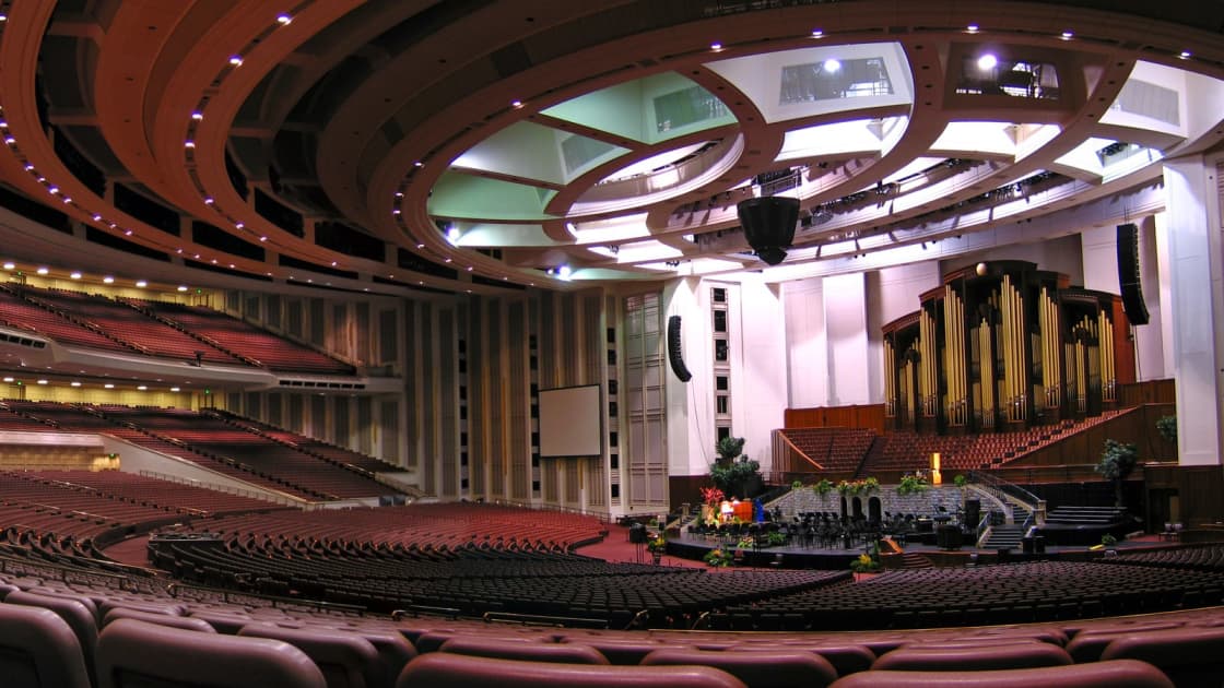 The empty auditorium of the Conference Center in Salt Lake City, its curving balconies of red seats sweeping toward the pipe organ and the rostrum