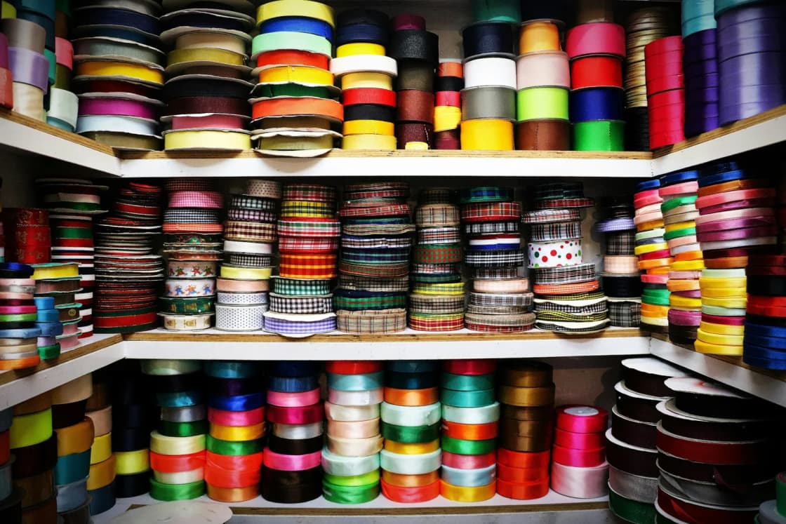 Shelves packed floor to top with spools of ribbon in every color, solid, striped and printed