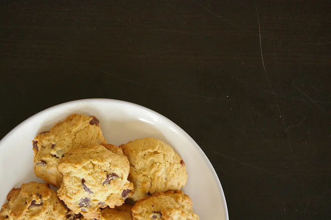 Chocolate chip cookies on a white plate against a dark background
