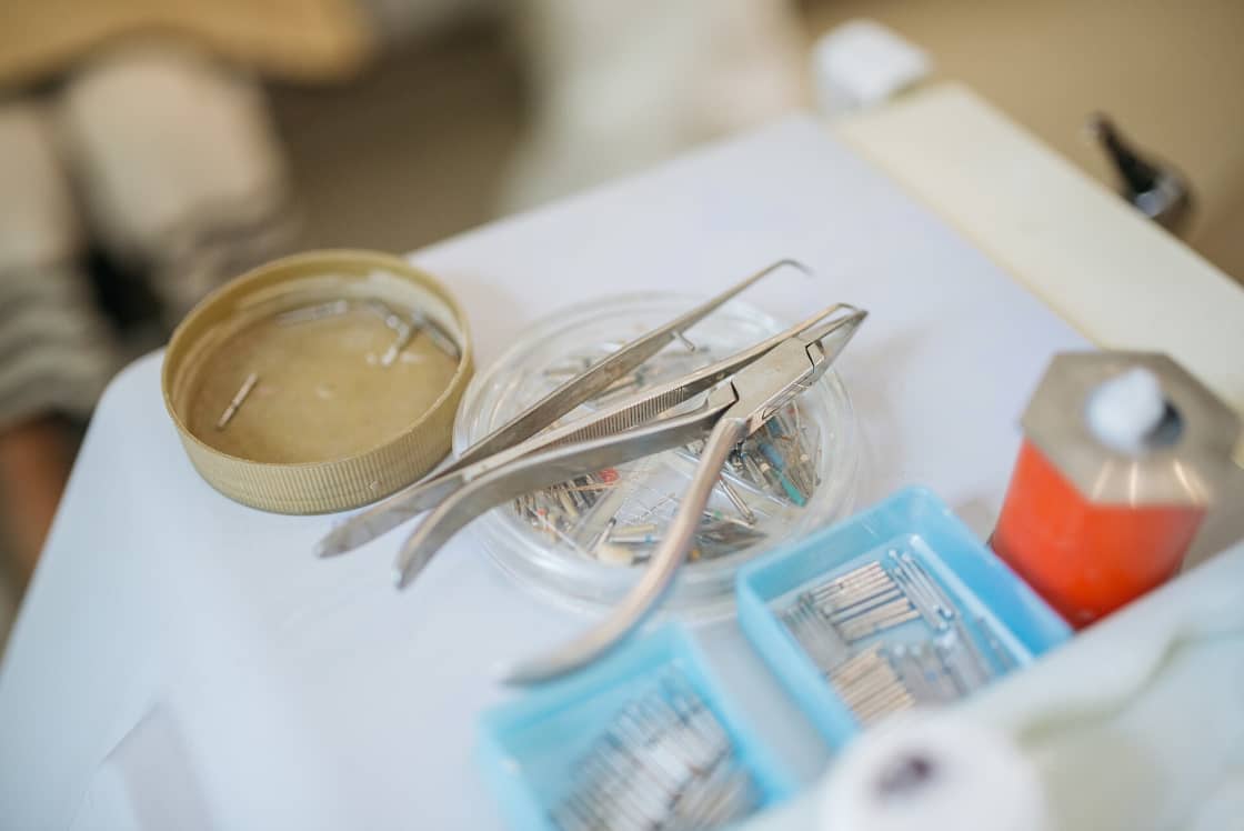 Stainless dental instruments and blue trays of burs laid out on a white clinic table