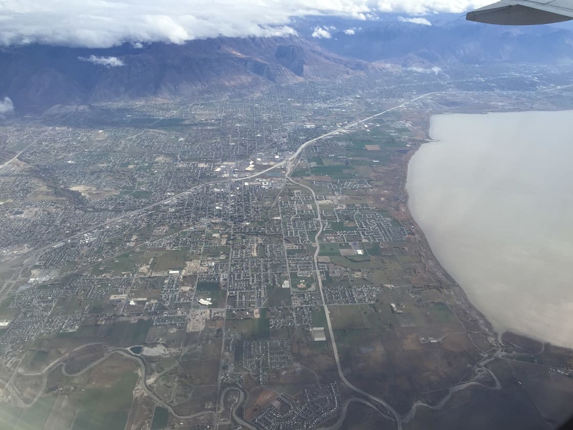 Aerial view over north Utah Valley showing the residential street grid, farm parcels, Utah Lake and the Wasatch Range beyond