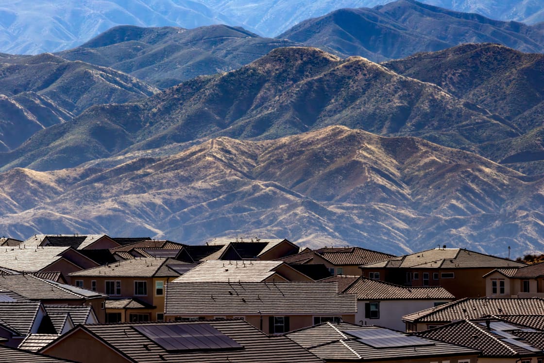 Rooftops of a suburban neighborhood with dry mountains rising behind
