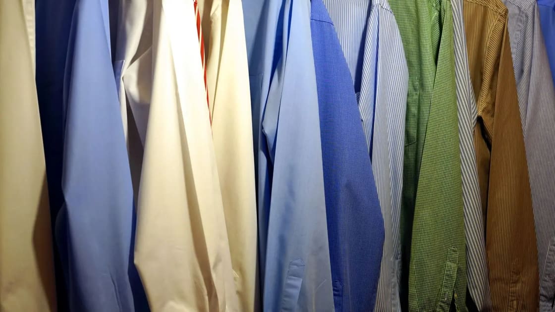 A packed rail of pressed shirts and jackets in blue, cream, green and striped fabrics