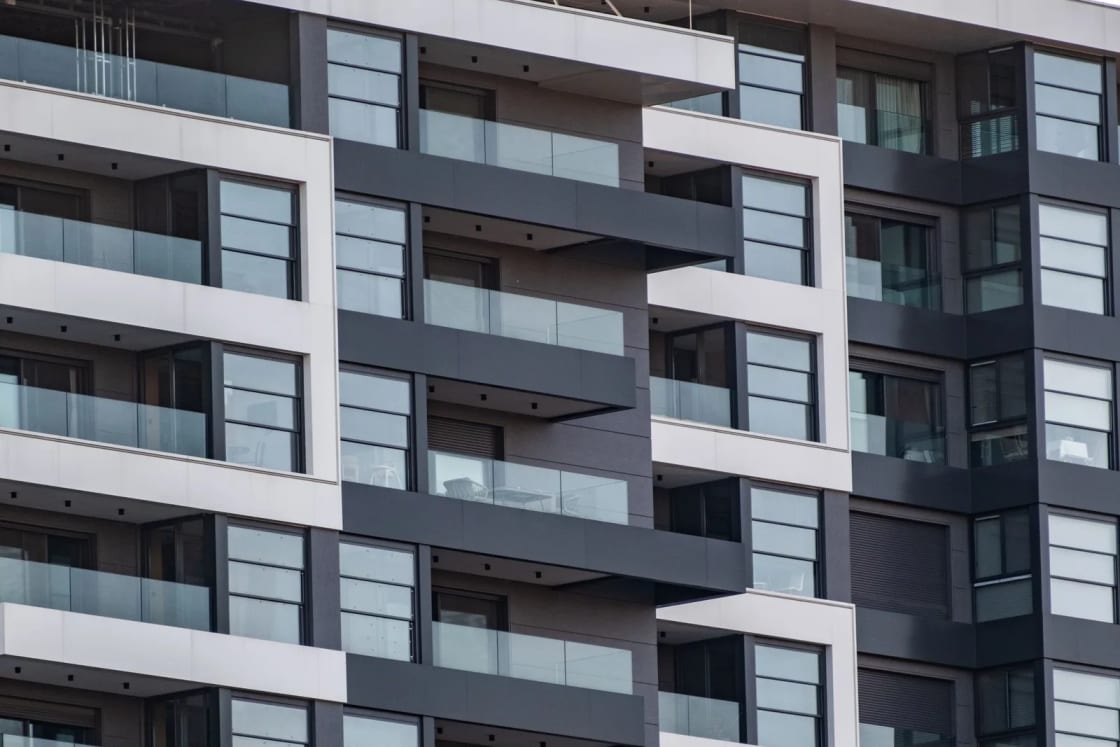 The gray and white facade of a modern apartment building with stacked balconies.