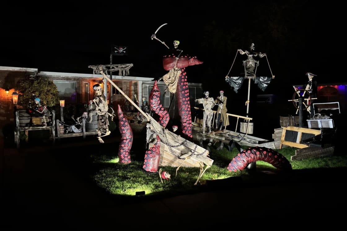 The Gibbs' American Fork front yard at night: a wrecked pirate ship with giant red Kraken tentacles, skeleton pirates on deck and in the rigging, and a skeleton captain at the wheel
