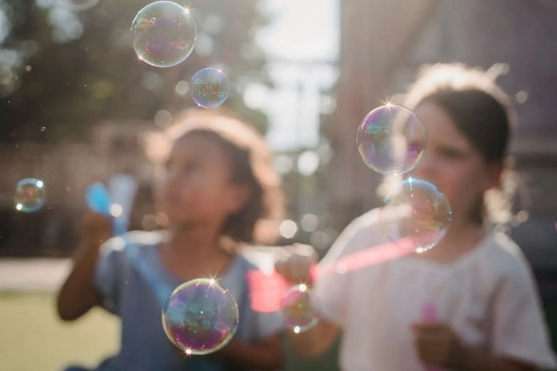 Young children enjoying a sunny day blowing bubbles, capturing joy and innocence