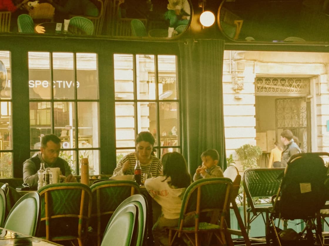 Families eating together at a cafe seen from the sidewalk