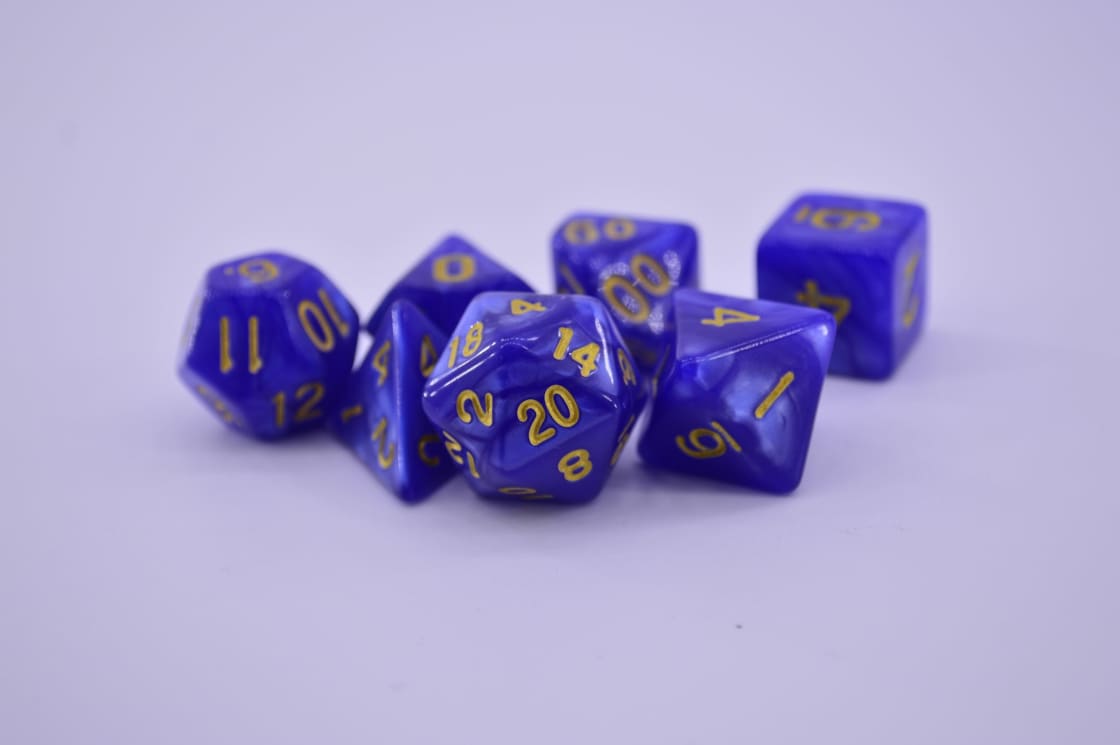 A set of seven blue-purple marbled polyhedral dice with gold numerals, grouped on a pale lilac surface, the twenty-sided die at the front showing 20