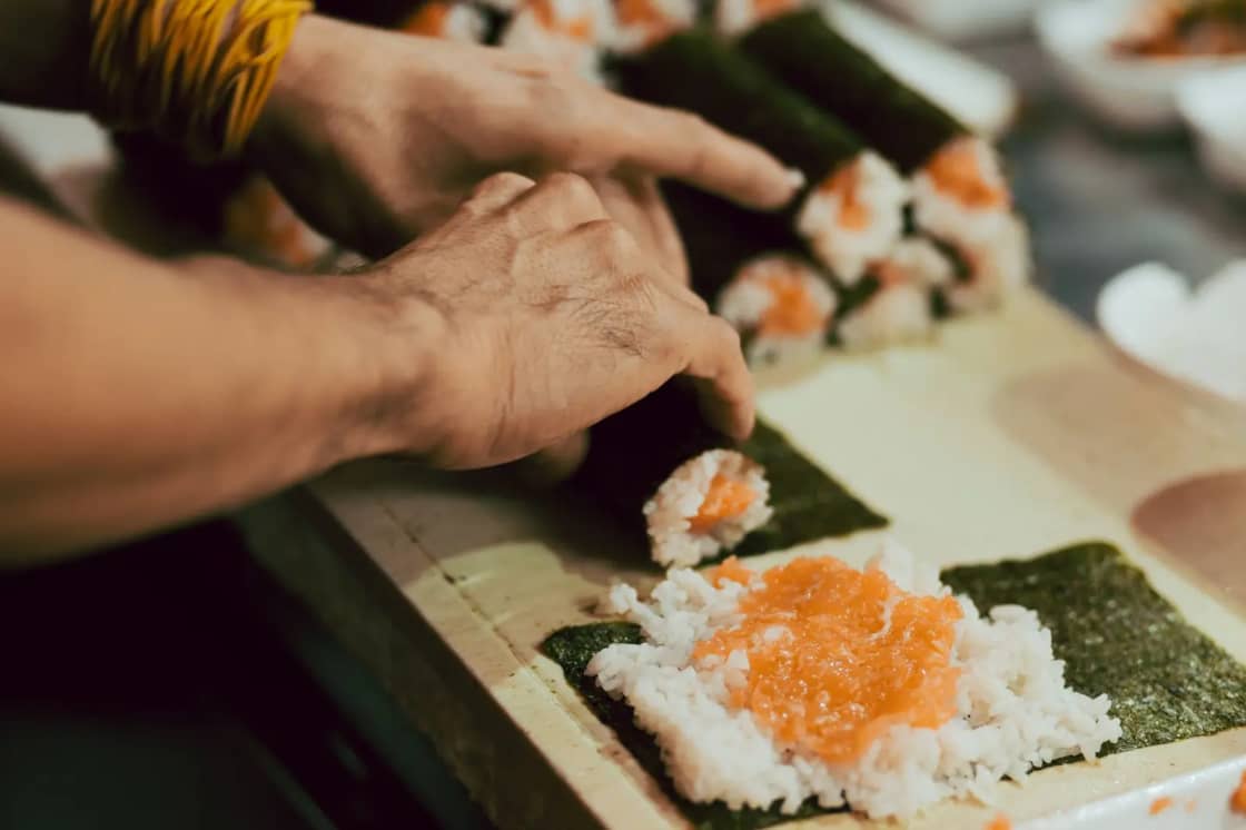 Close-up of sushi being rolled with rice and salmon
