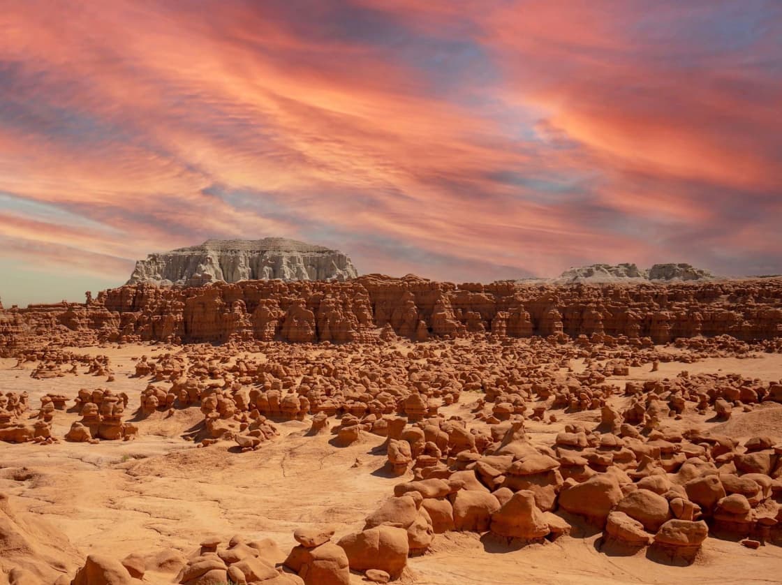 A desert floor covered with thousands of rounded rock formations under a streaked orange sky
