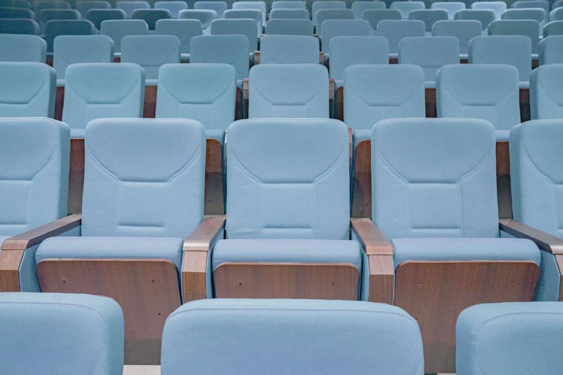 Rows of pale blue upholstered theater seats in an empty auditorium