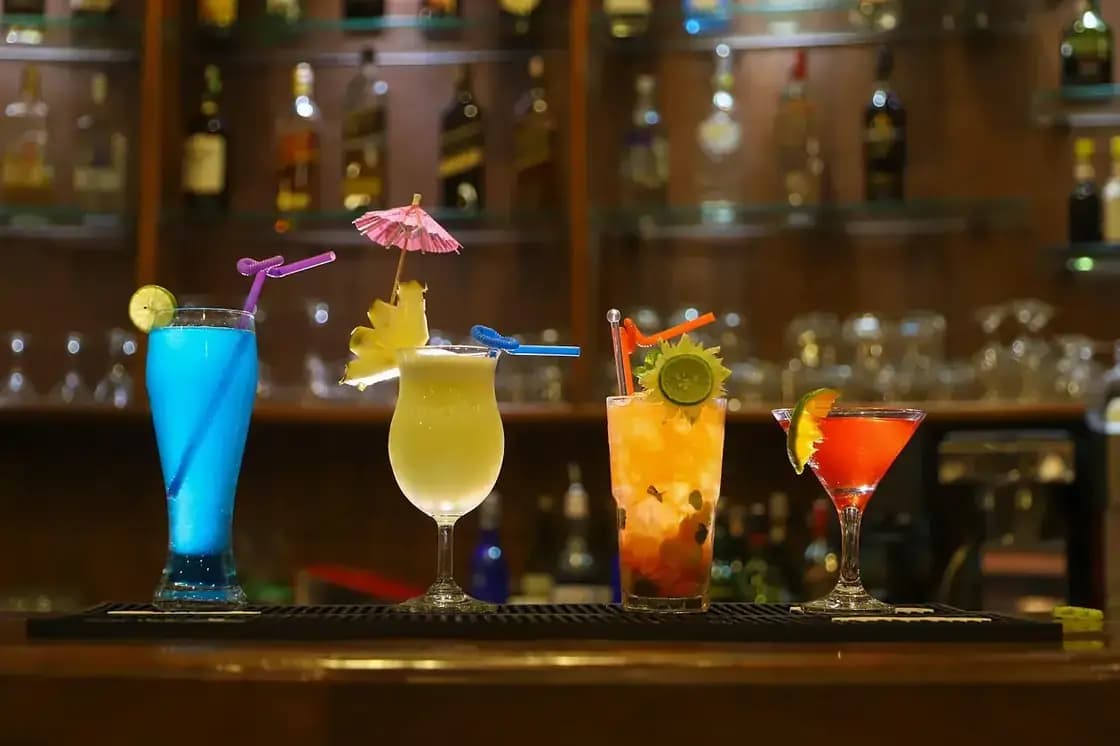 Brightly colored drinks lined up along a bar