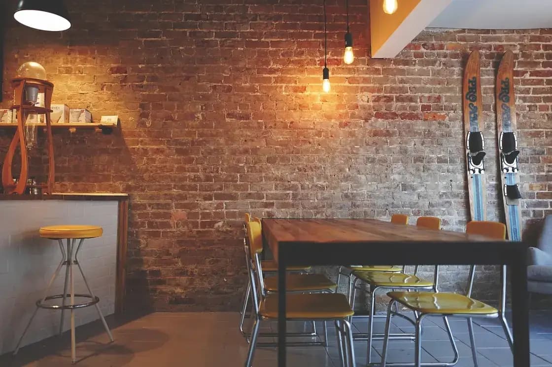 An empty cafe interior with exposed brick walls and hanging bulbs