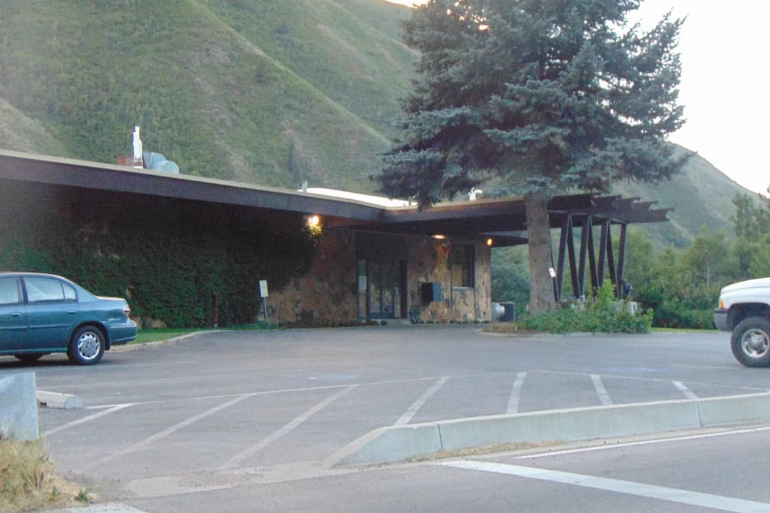 The low stone clubhouse at Hobble Creek Golf Course in Hobble Creek Canyon, with its parking lot and green hillsides behind.
