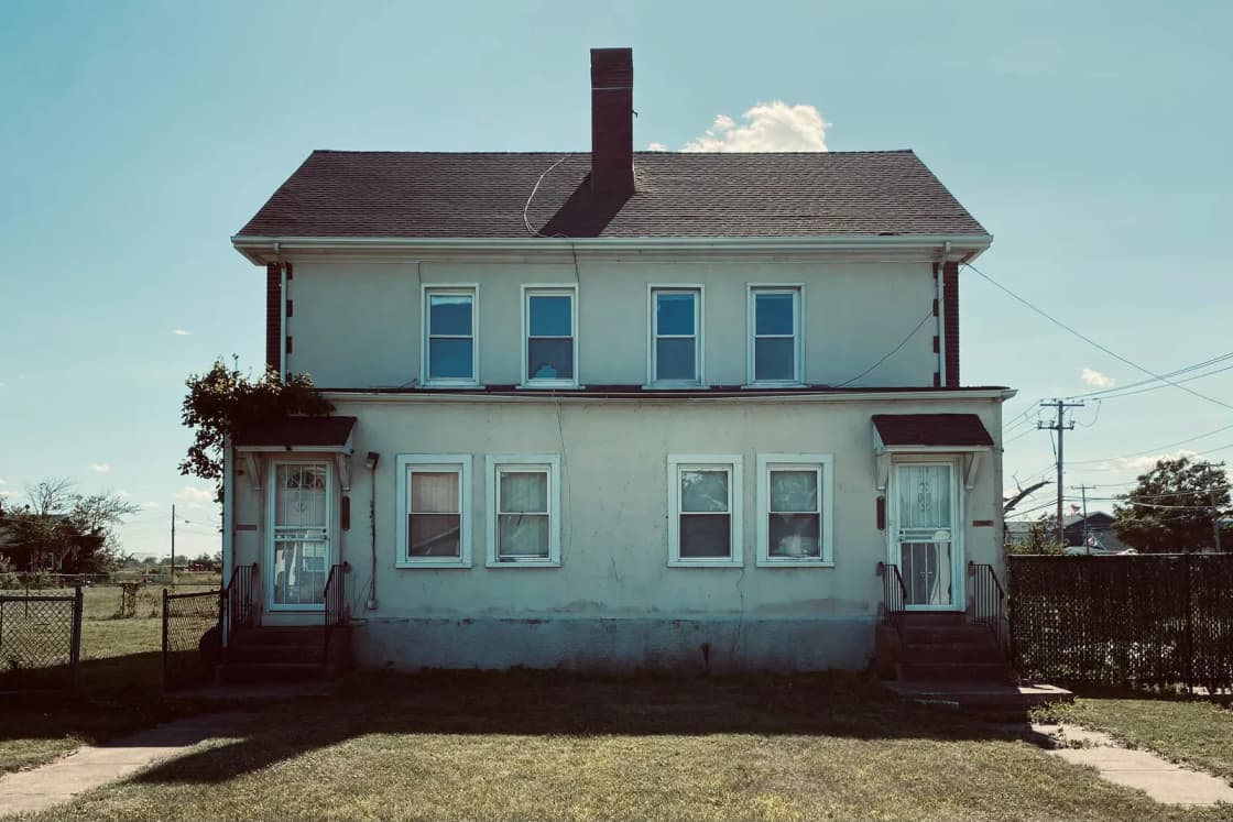 A two-story, two-unit house with separate entrances and a small fenced yard.