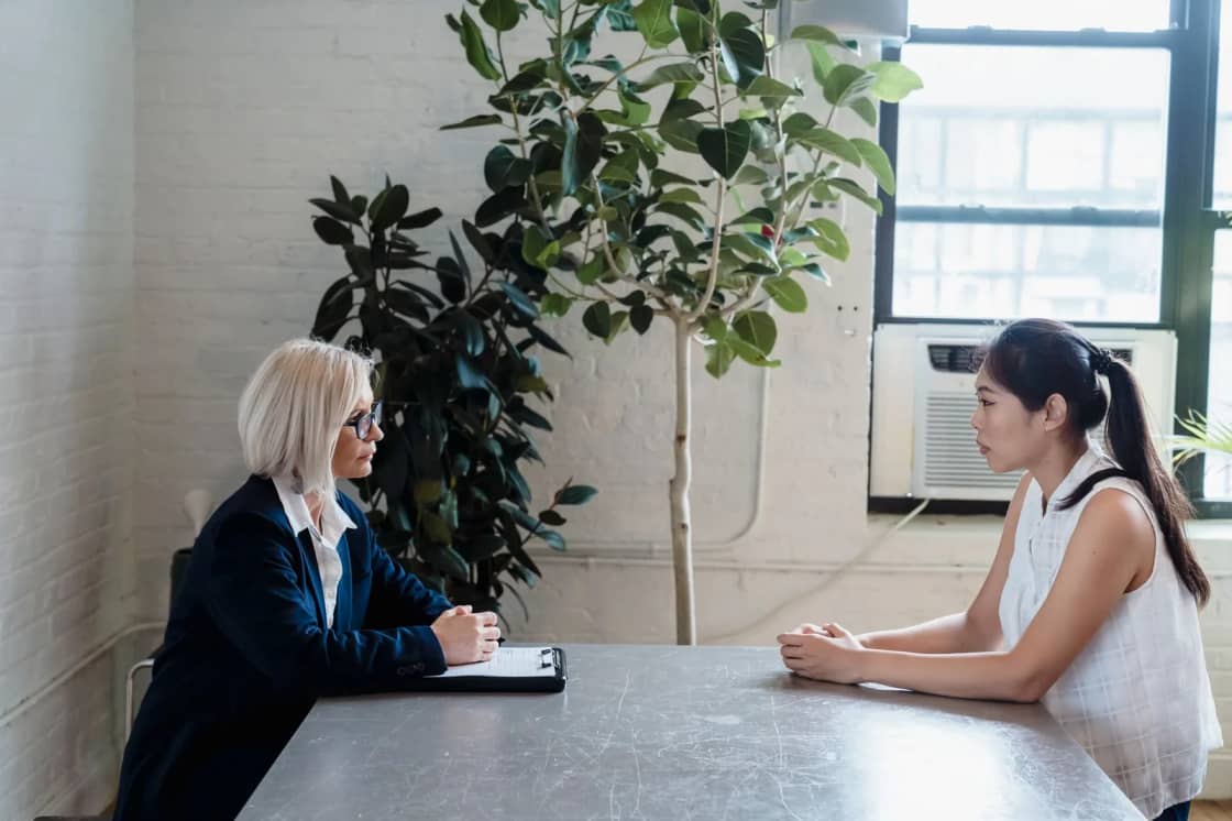 Two people sitting across a table from each other during a one-to-one interview