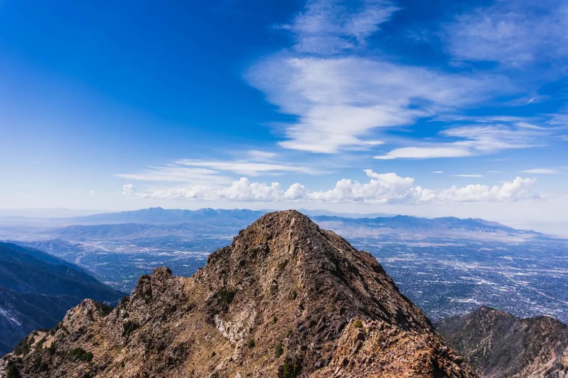 Breathtaking view from a mountain peak overlooking a cityscape beneath a vibrant blue sky