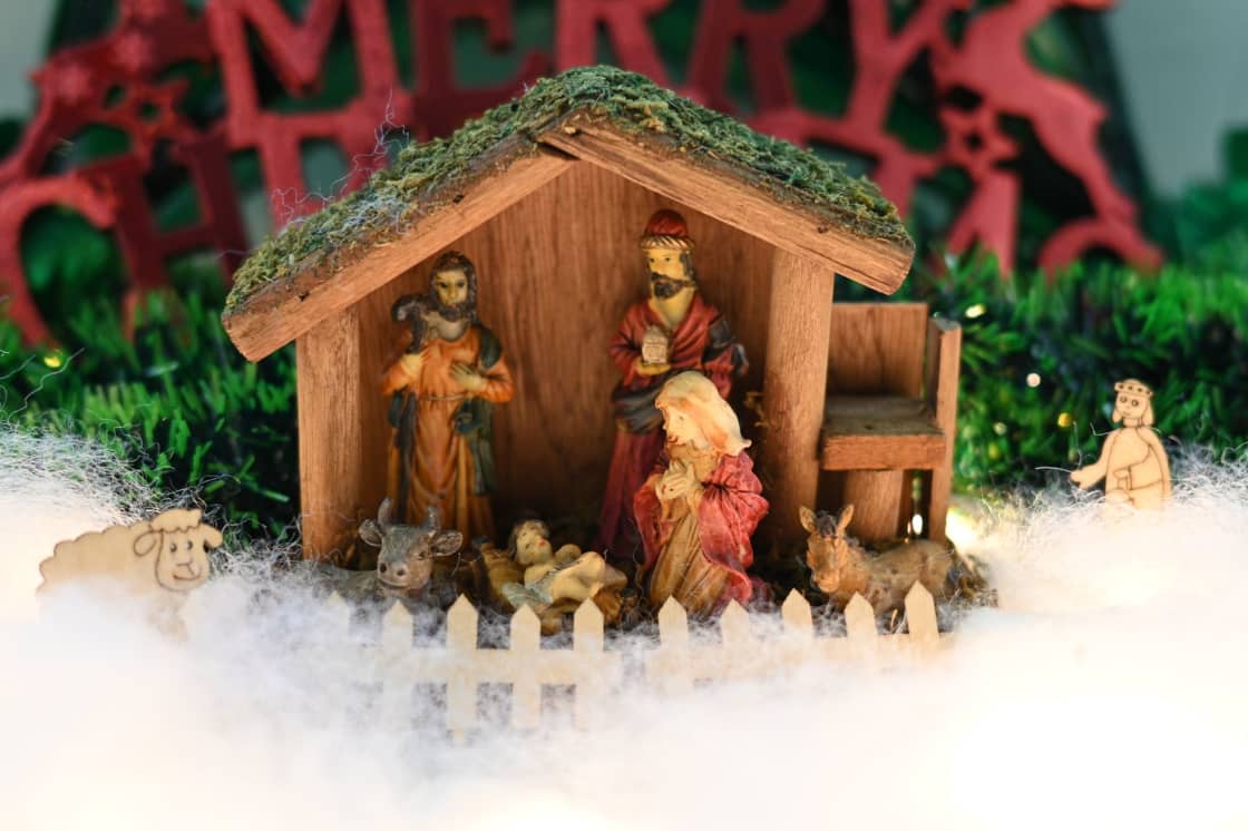 A wooden nativity stable with painted figures of Mary, Joseph, the infant, an ox and a donkey