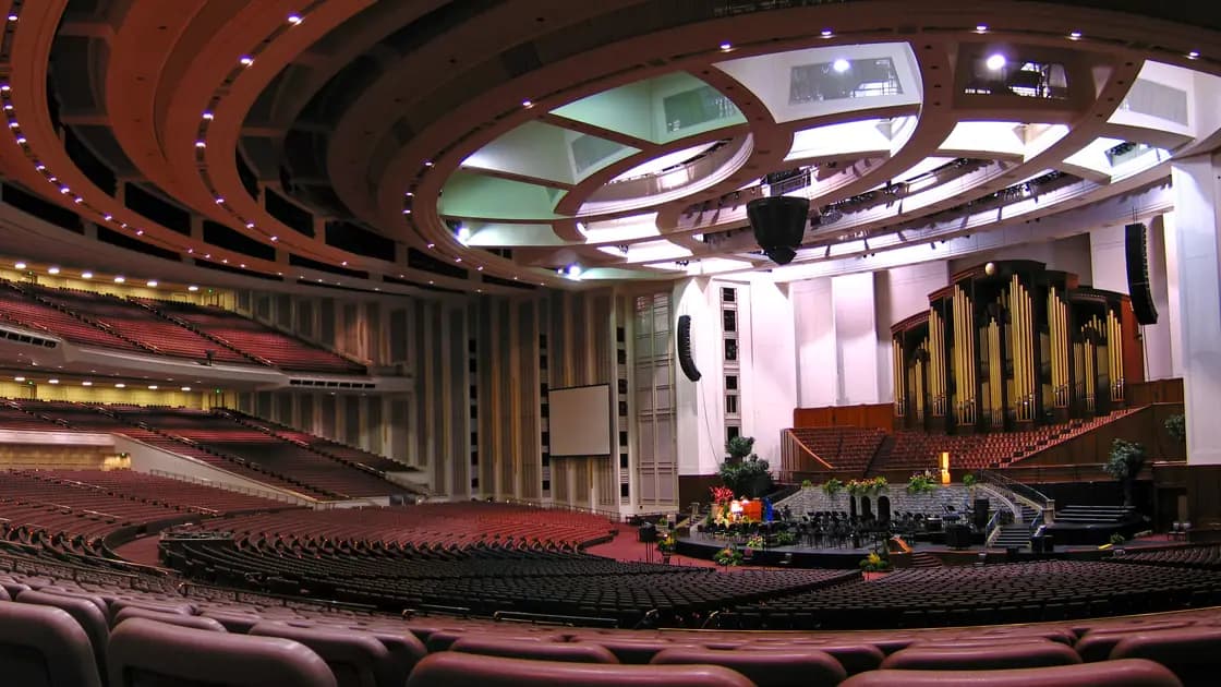 Rows of empty red seats facing the rostrum and pipe organ inside the Conference Center in Salt Lake City