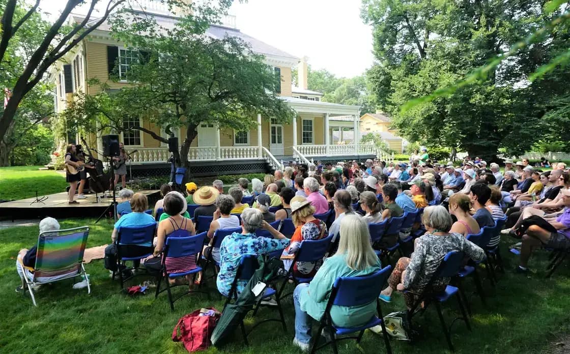A large crowd gathered on a lawn at an outdoor summer festival