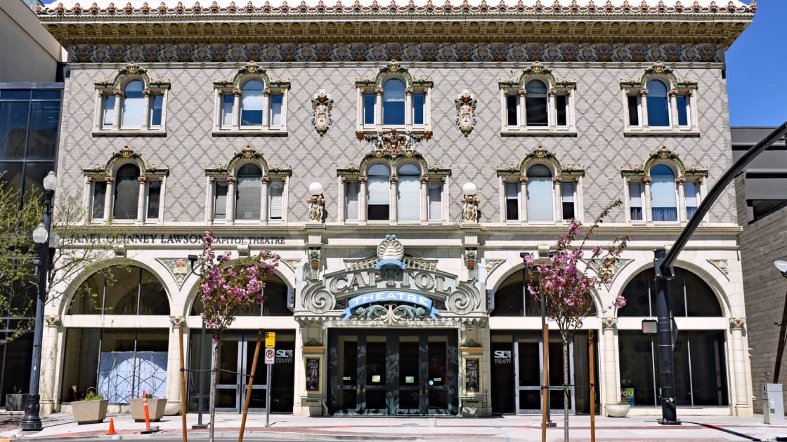 The ornate terra-cotta front of the Capitol theater in downtown Salt Lake City, Ballet West's home, with arched windows, carved detail and its marquee over the entrance on a clear spring day