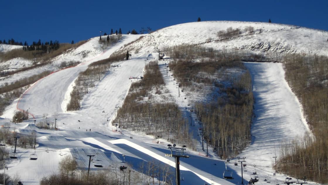 The Eagle Race Arena at Park City Mountain, groomed race runs cut through bare aspens with chairlifts climbing the slope under a deep blue winter sky