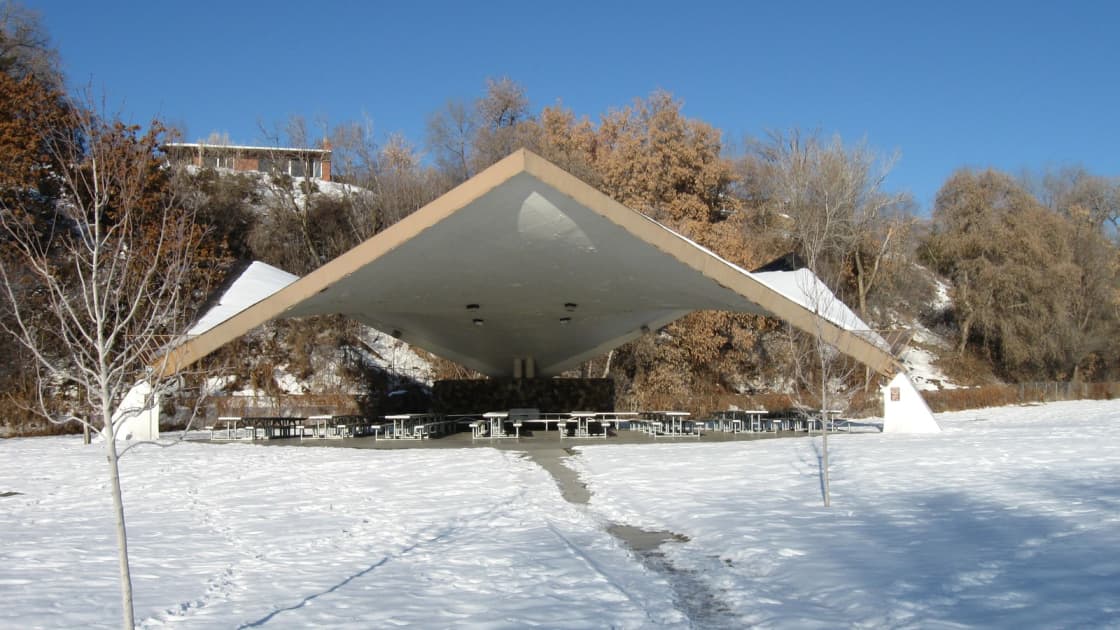 The tent-like white pavilion at Lions Park in Provo standing on a snow-covered lawn under a blue winter sky