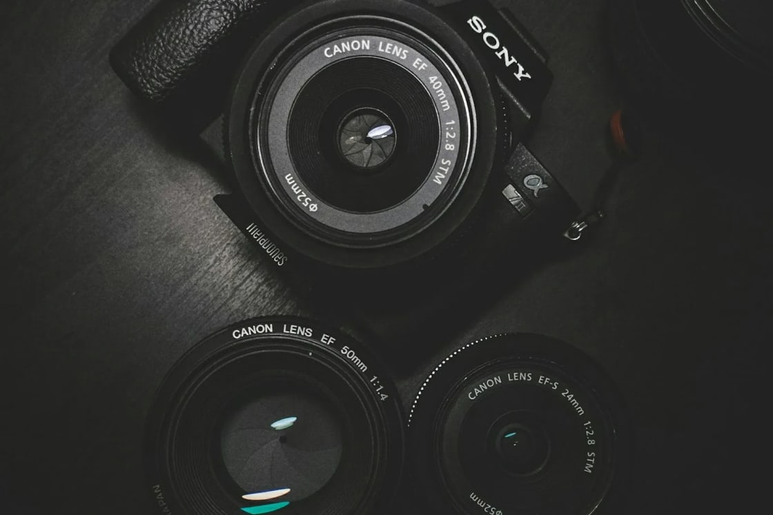 A mirrorless camera body and two spare prime lenses laid out on a dark tabletop, ready for a class or a photo walk