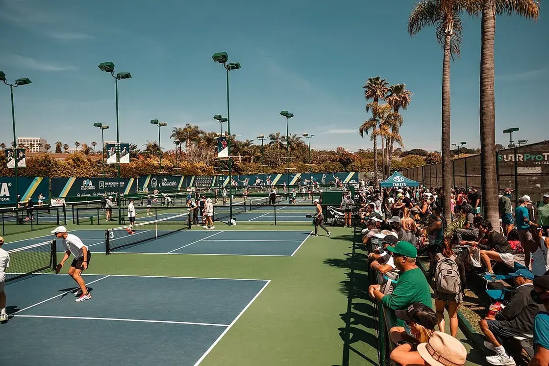 Doubles pickleball players mid-rally on an outdoor court