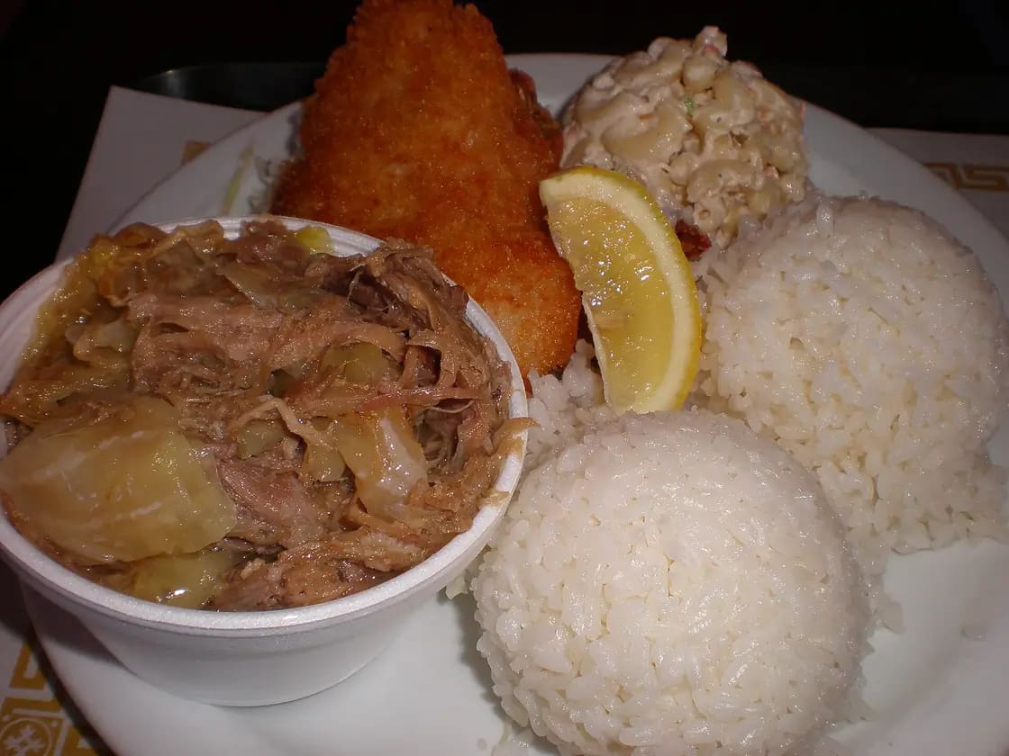 A Hawaiian plate lunch of two scoops of white rice, a scoop of macaroni salad, a breaded fried cutlet and a cup of shredded kalua pork with cabbage