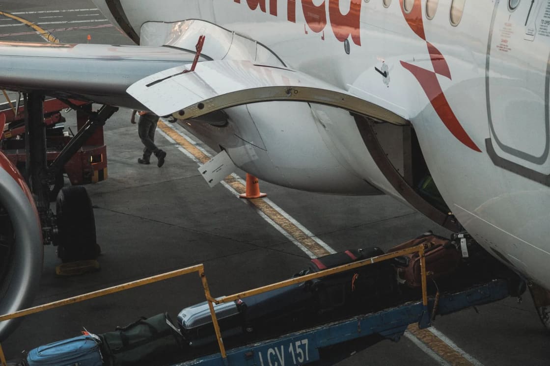 Suitcases moving up a belt loader into the hold of a parked airliner